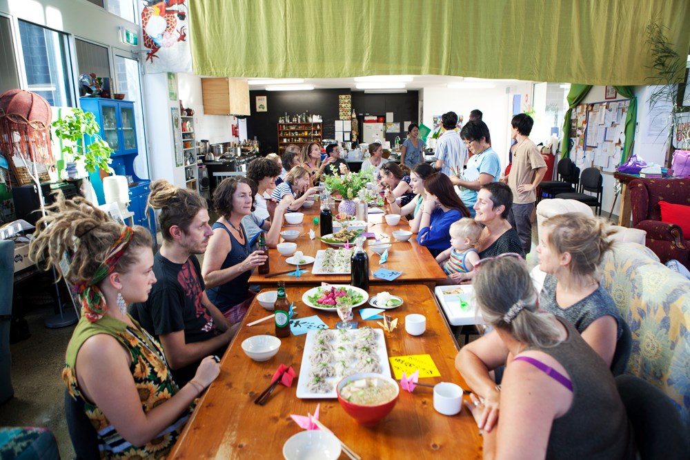 Photo of diverse people having a meal across several wooden tables